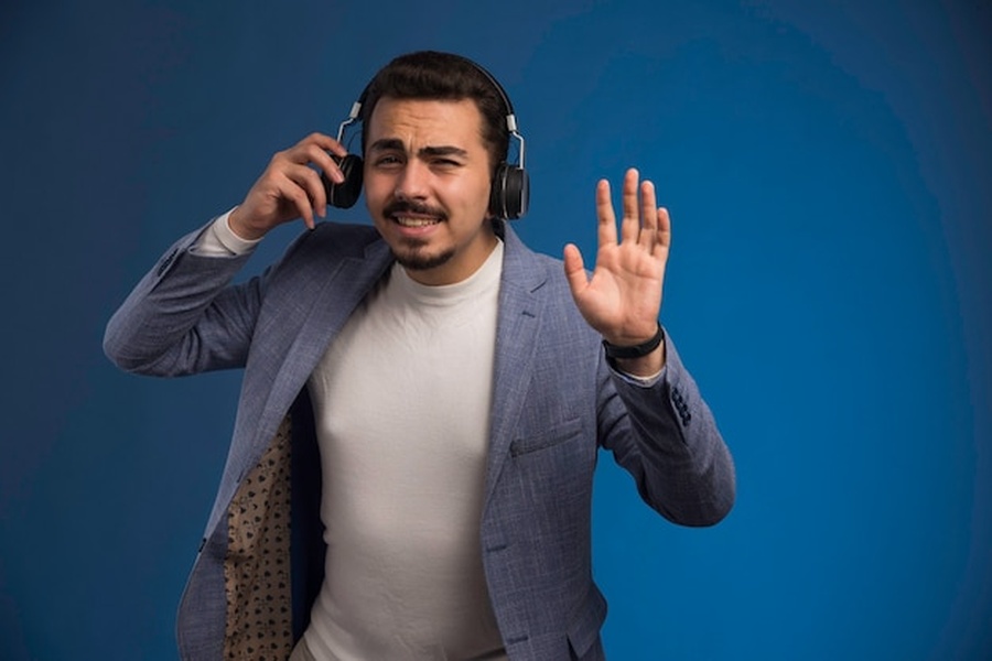 Un homme avec un casque audio exprime son désaccord, illustrant comment attaquer une plateforme pour usage non autorisé de votre voix par une IA en 2026.