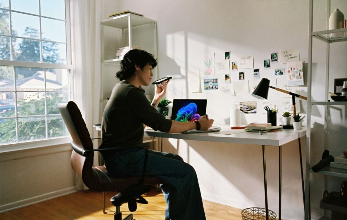 Un créatif utilise son smartphone et son ordinateur portable dans un bureau lumineux, illustrant l’utilisation d'un Guide AI pour optimiser sa productivité au quotidien.