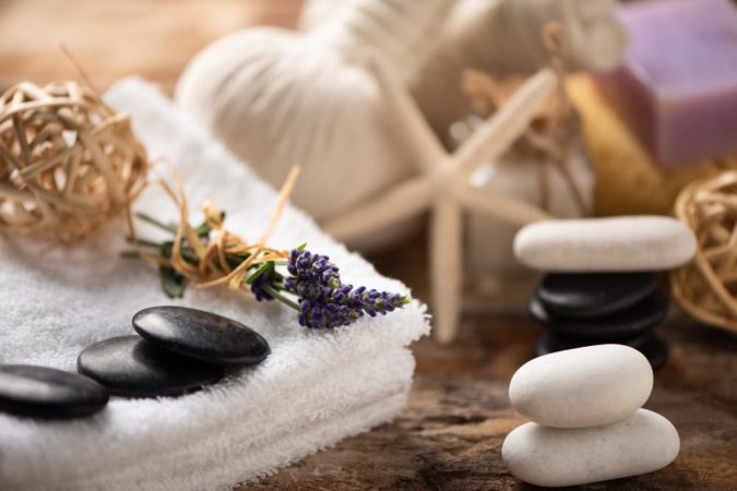 Accessoires de relaxation dans un centre de bien être incluant des pierres chaudes, de la lavande et des pochons de massage.