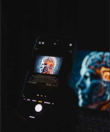 Gros plan d'un smartphone capturant une image de cerveau numérique sur un écran d'ordinateur, illustrant comment utiliser les Guides AI pour comprendre l'intelligence artificielle.