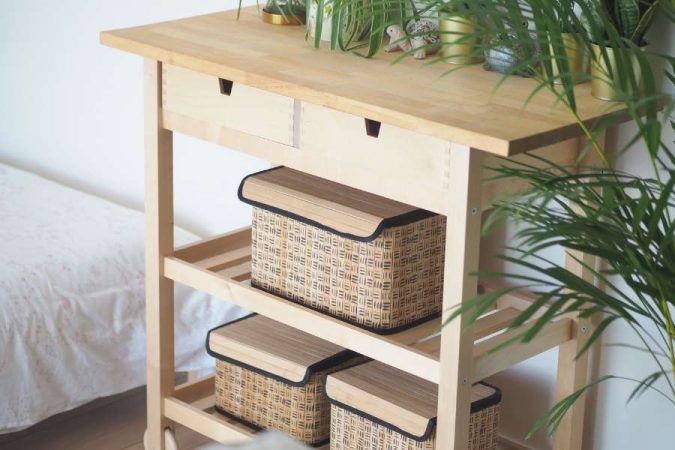 Des paniers à motifs tressés disposés sur une desserte en bois clair comme solutions de rangement.