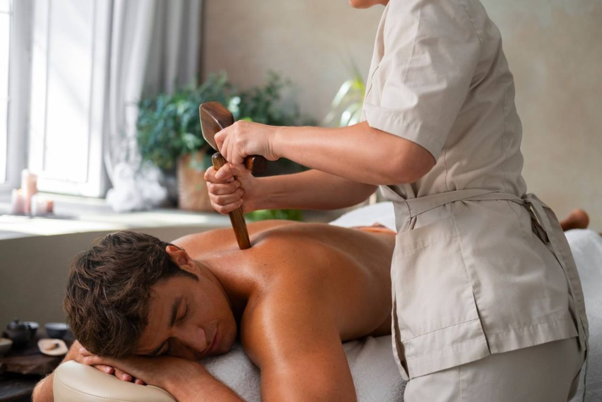 Praticienne appliquant un soin du dos avec un outil en bois dans le cadre d'un massage lomi lomi tradition hawaïenne.