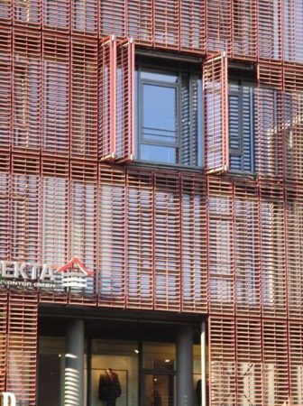 Façade moderne d'un bâtiment équipée de brise-soleil rouges et de châssis en PVC Kömmerling pour une isolation optimale.