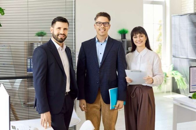 Une équipe de professionnels en costume pose dans un bureau moderne pour illustrer comment ouvrir société à Dubaï.