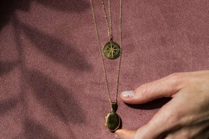 Une chaîne de baptême dorée avec un pendentif étincelant tenue par des mains.